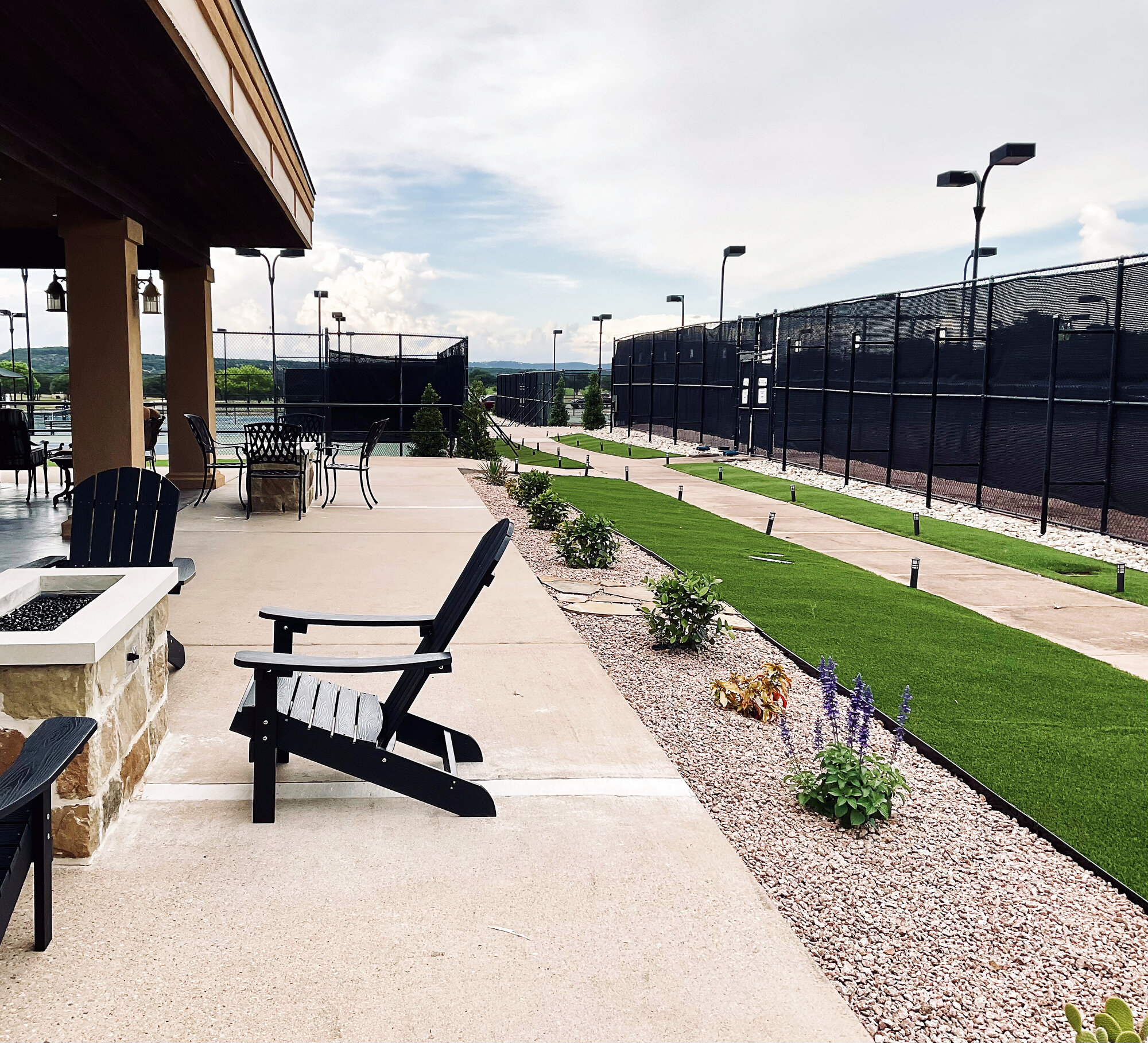 The Lakecliff patio at dusk — gas firepit, lounge chairs, and the courts beyond
