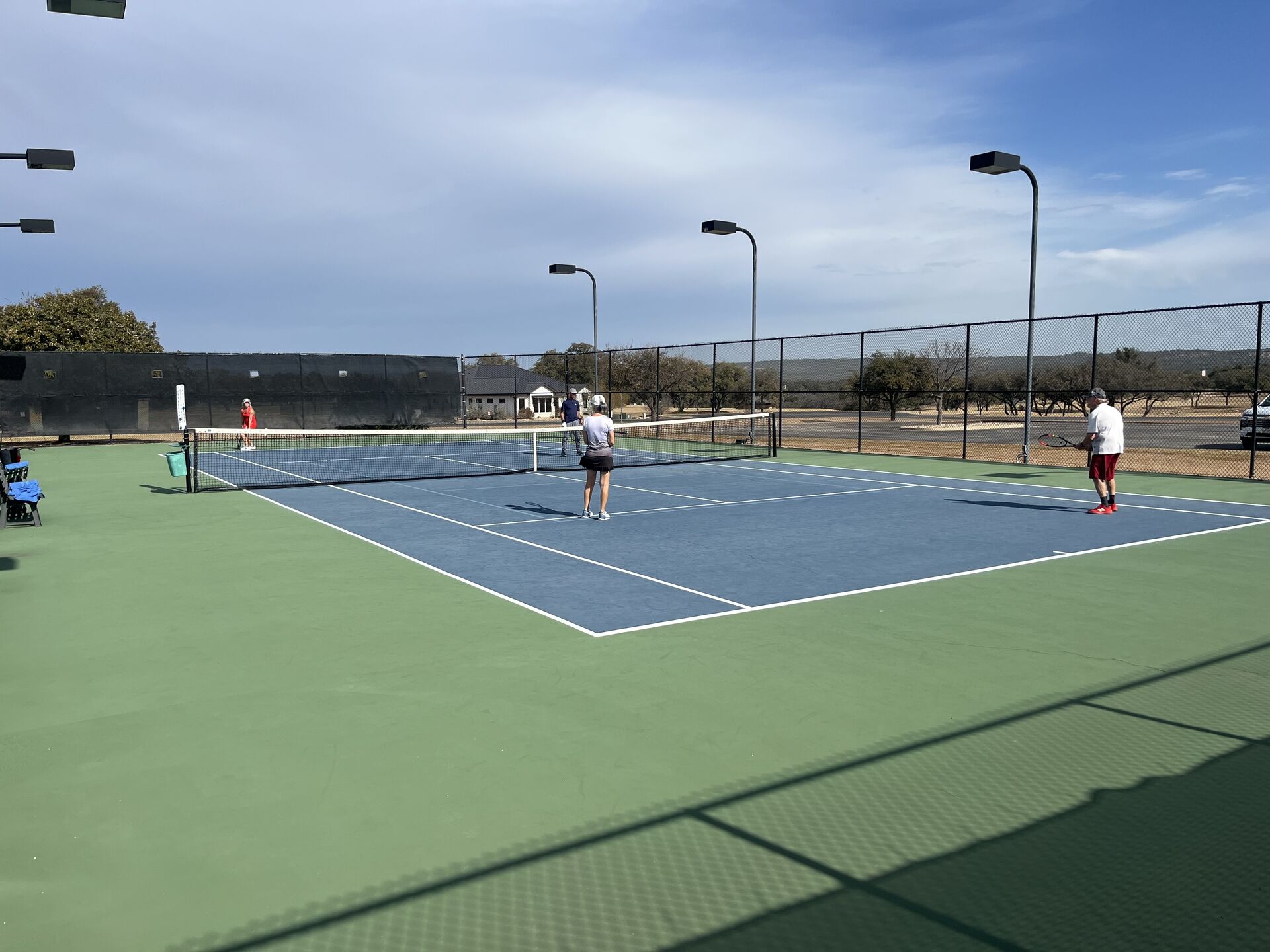 Members playing tennis on a hard court at Lakecliff Racquet Club